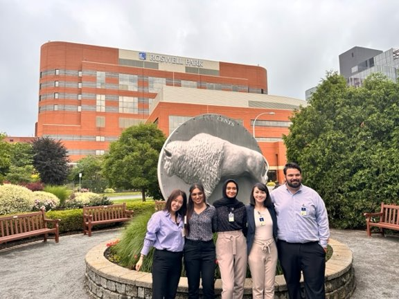 Four students from the Oncology Pharmacy Residency Program pose in front of Roswell Park's main campus