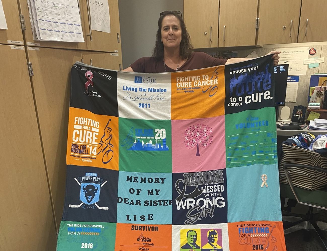 Woman holding a quilt she made from old t-shirts