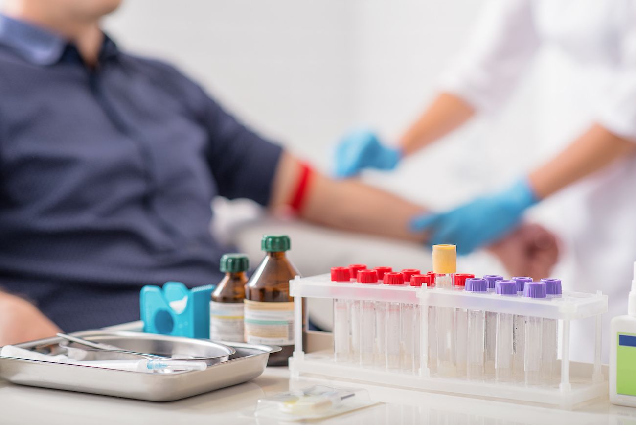 Test tubes on a table while a person gets prepped for a blood test