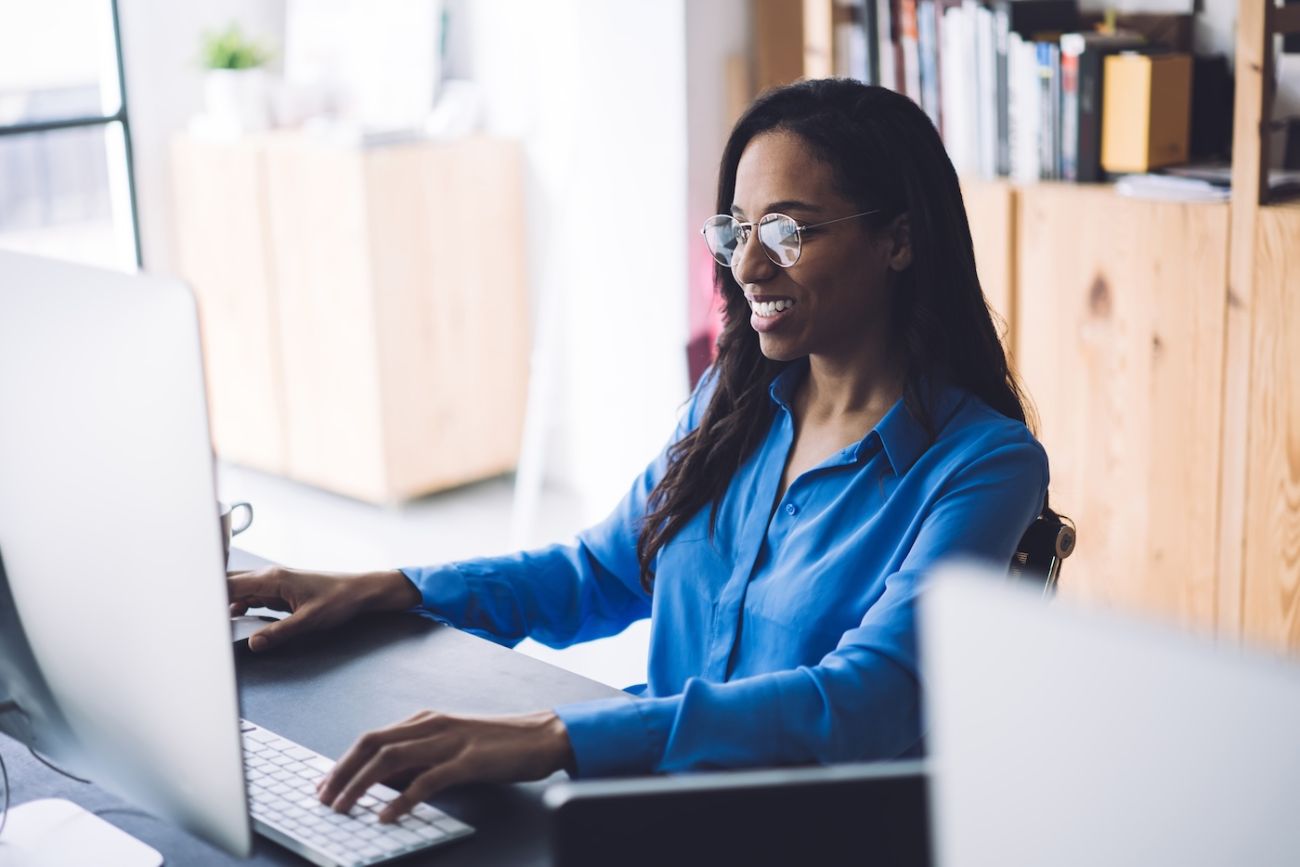 Woman sitting at a desk watching a webinar on her computer