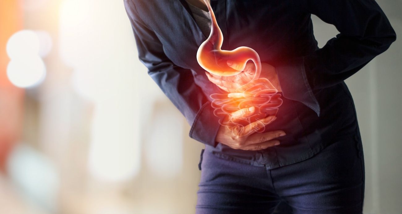 Person holding their stomach in pain with a drawing of the digestive system