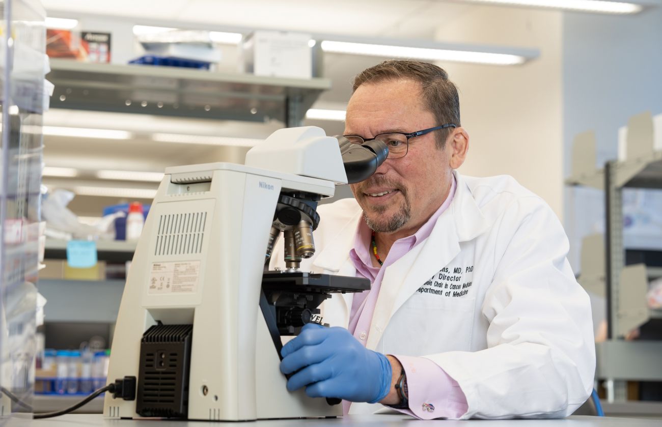 Deputy Director Renier Brentjens, MD, PhD, studies something with a microscope.