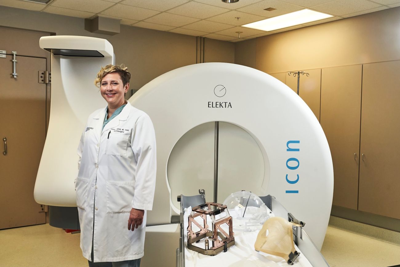 Dr. Lindsay Lipinski stands in front of Gamma Knife radiosurgery equipment