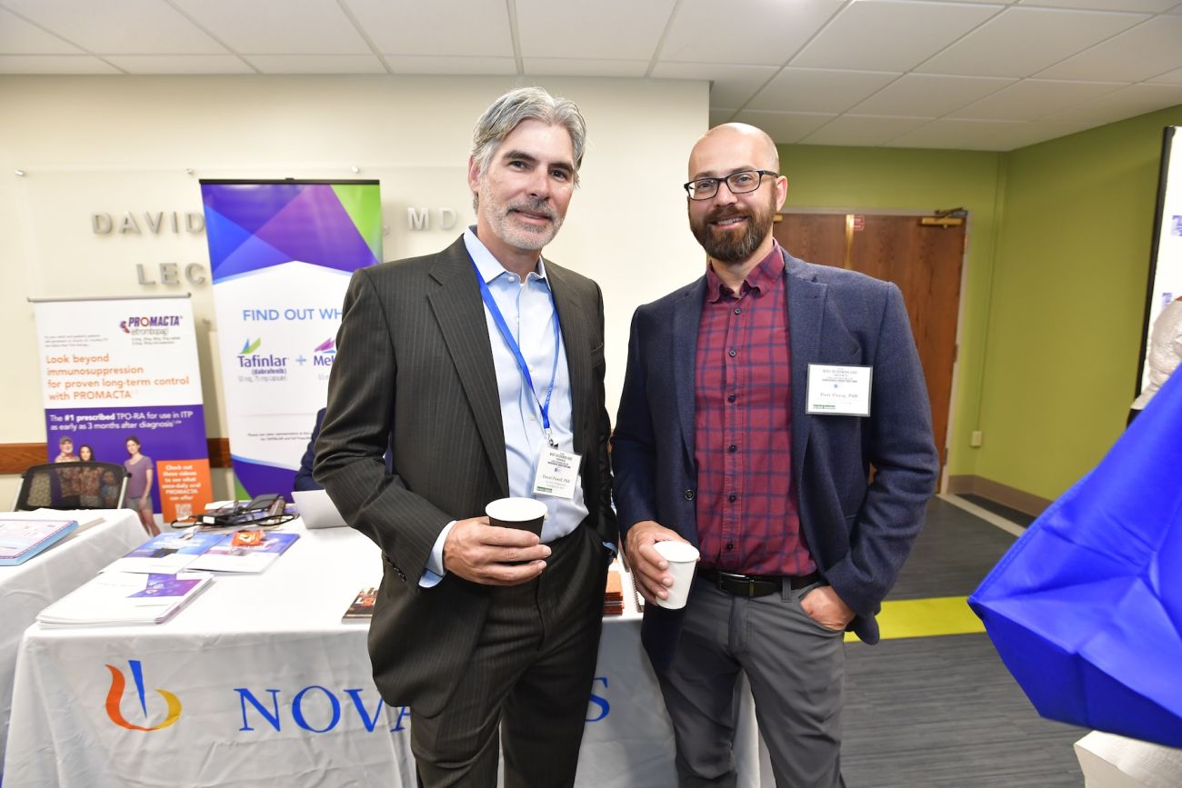 Two cancer scientists posing by an informational table