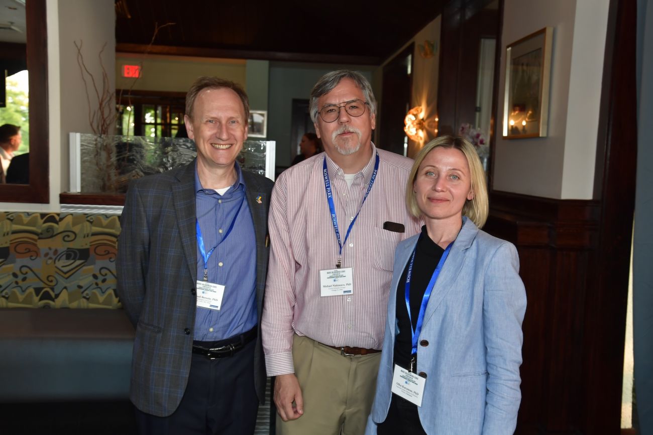 Three researchers smile at a social event