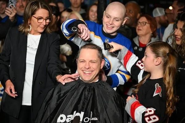 A cancer survivor shaving the head of someone for charity