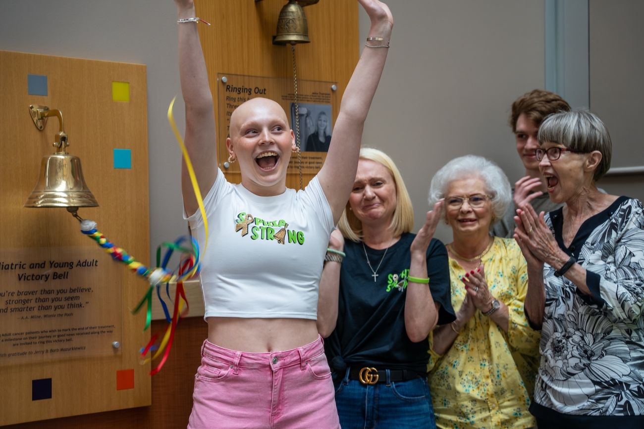A cancer survivor cheers while ringing the victory bell in a hospital