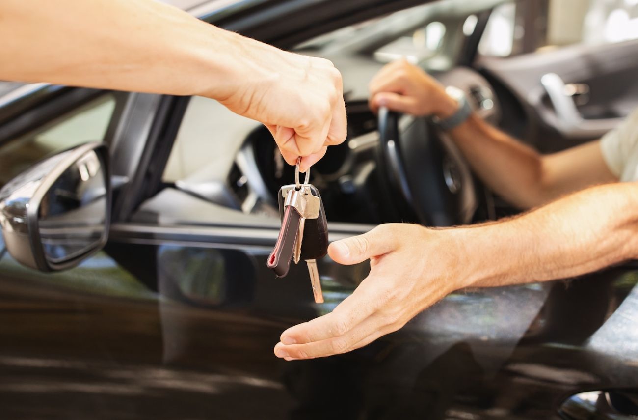 A person in a car handing their keys to the valet service