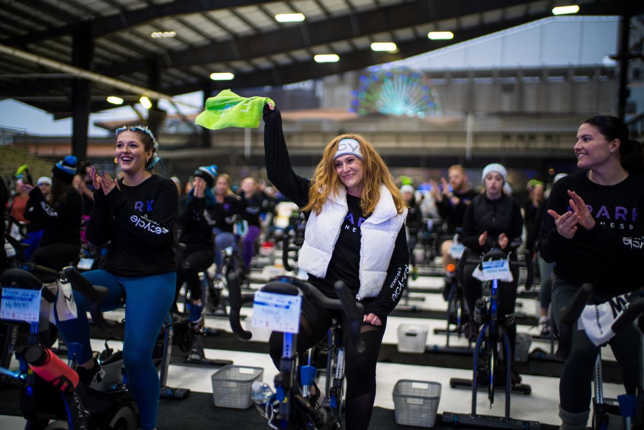 Woman riding a stationary bicycle, waving a rally towel