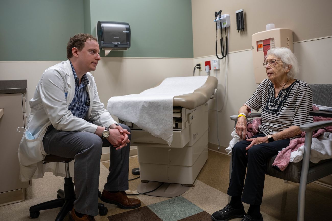 A doctor speaks with an elderly patient in an exam room