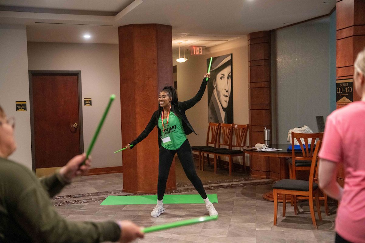 A woman leads a group of patients in a Pound Fitness class at 100 College Parkway location