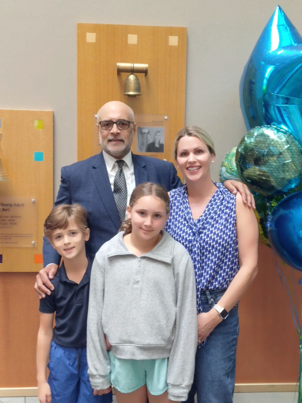 Multiple myeloma patient Adam Perry poses with his wife and children after ringing the Victory Bell