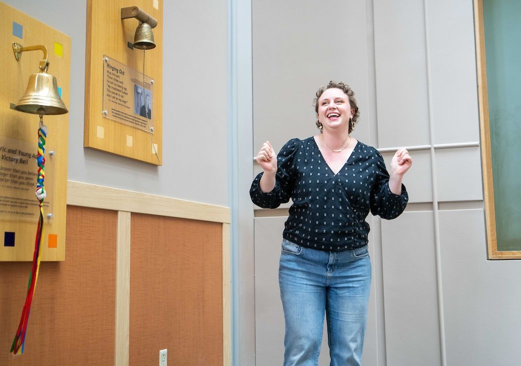Hannah, a breast cancer patient and survivor, celebrates after ringing the Victory Bell