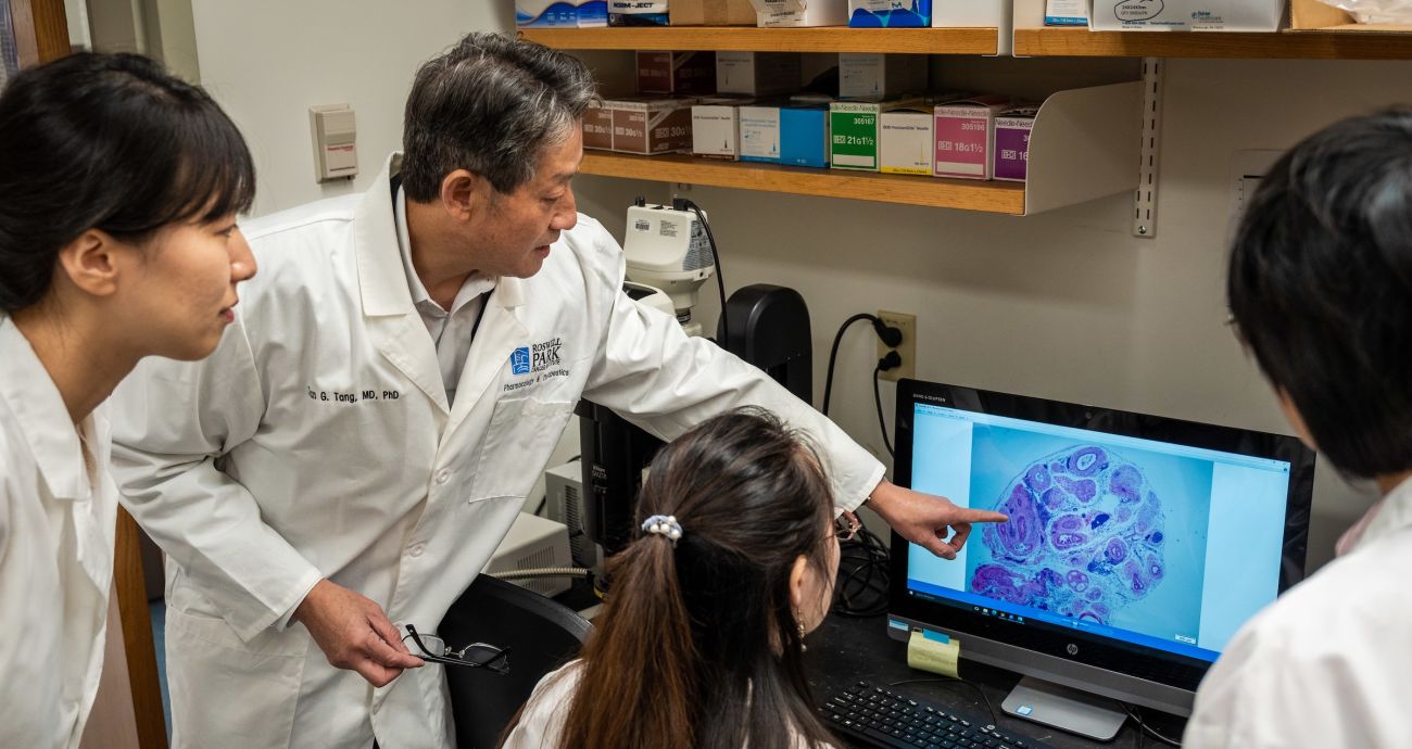 A doctor examines a cell slide with lab members