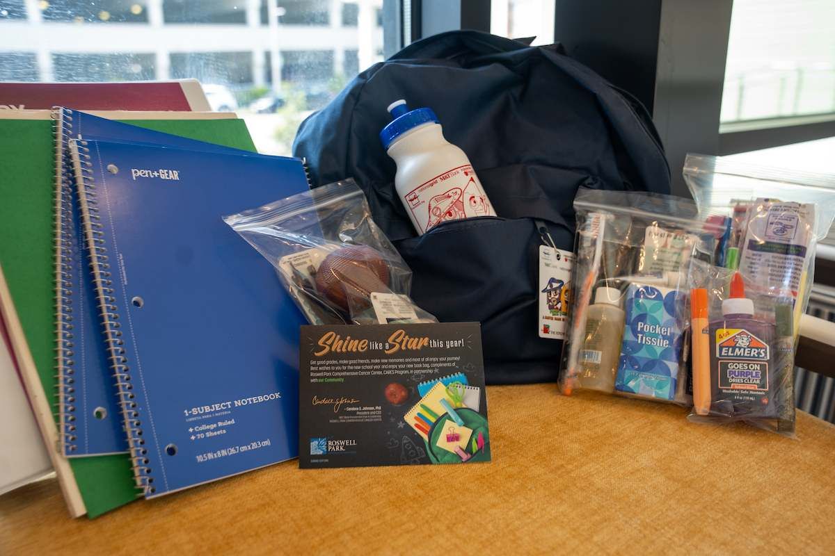 School supplies and a backpack on a brown table top. 