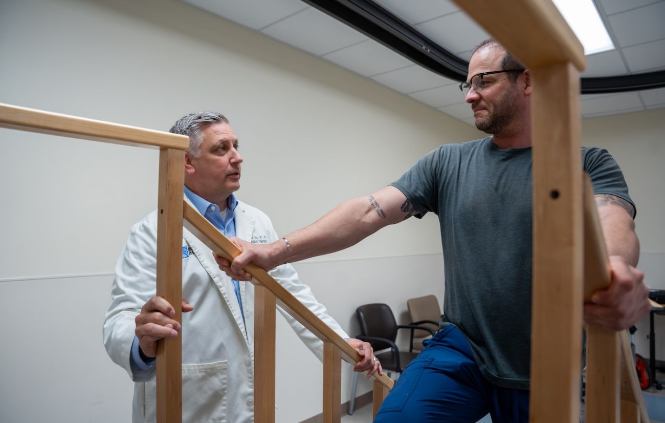 Dr. Andrew Ray observes a patient in the rehab center doing strength training exercises