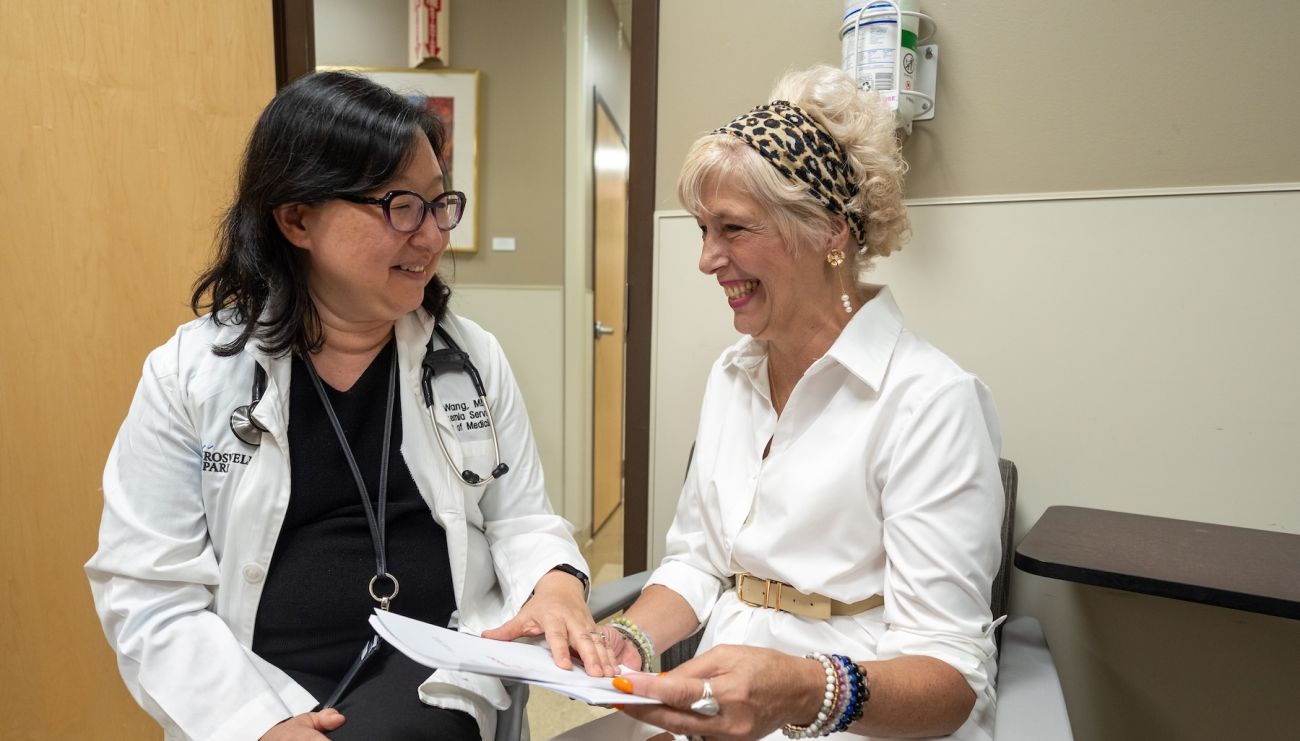 A doctor speaks with a female patient in an exam room
