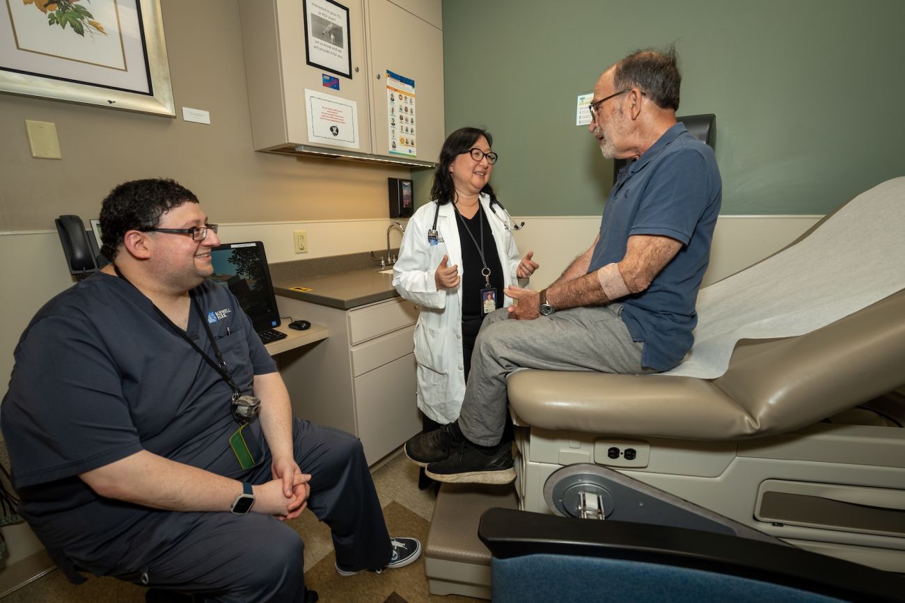 A doctor and pharmacist consult with a patient in an exam room