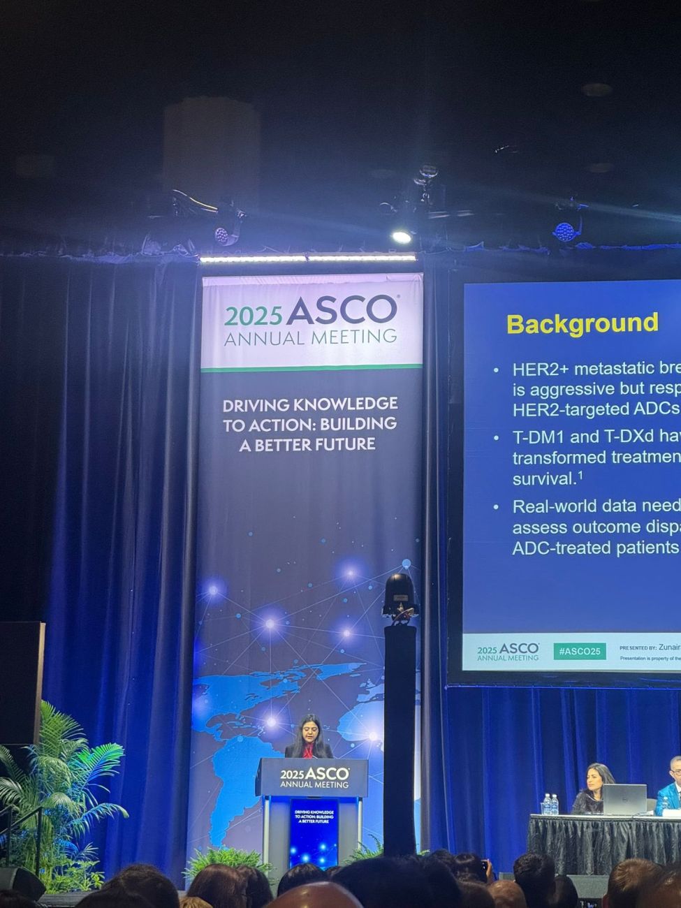 Zunairah Shah, hematology oncology fellow, stands on a stage at ASCO 2025 giving an oral presentation