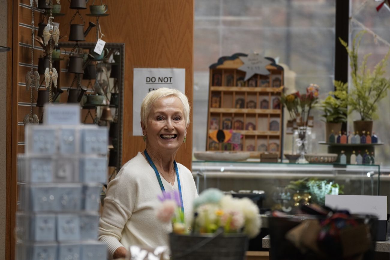 An elderly woman works the front desk at a gift shop