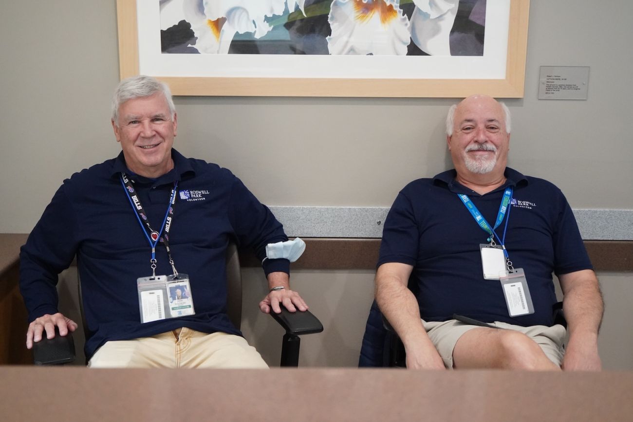 Two male volunteers sit and wait for a task inside a hospital