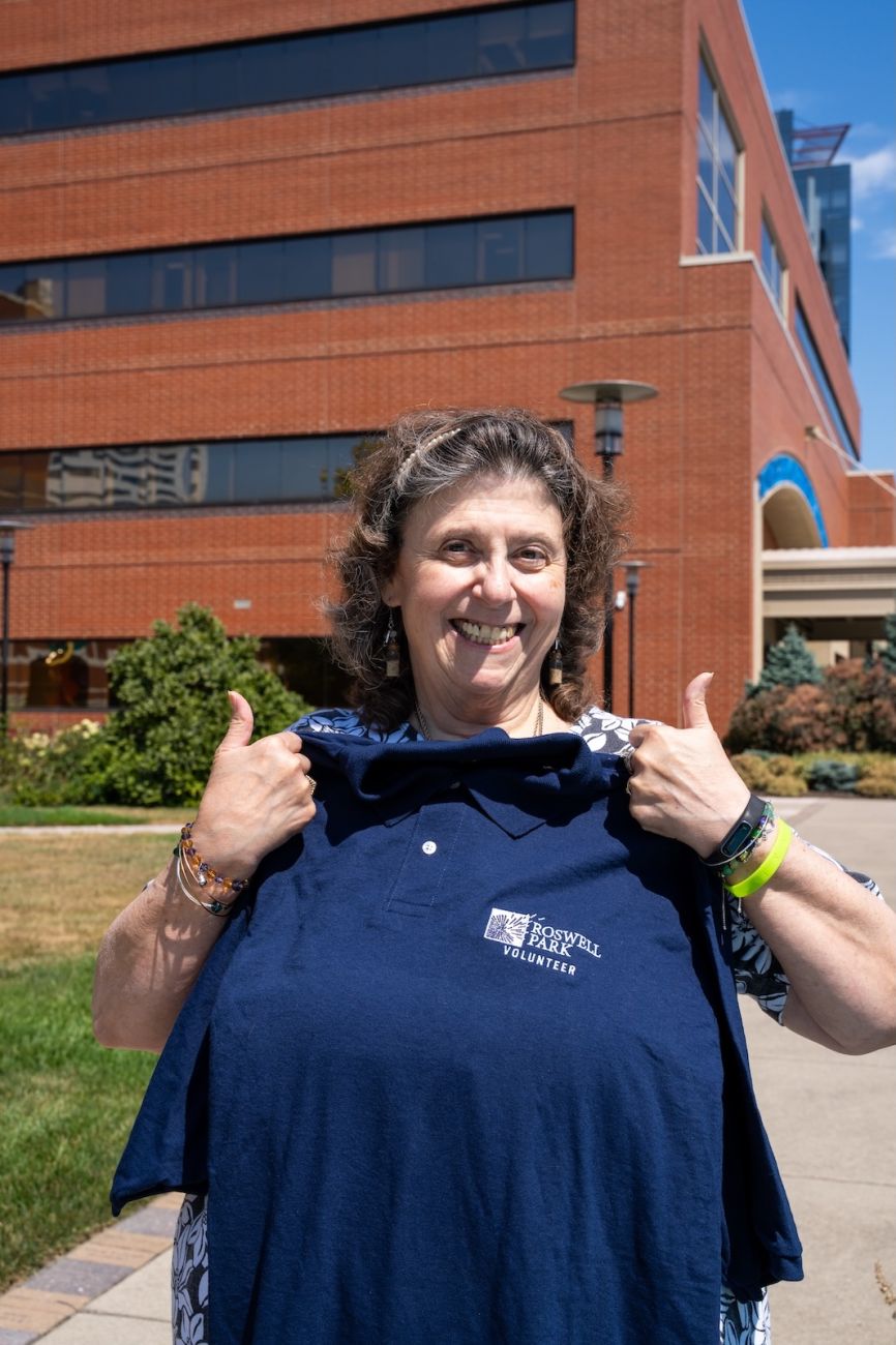 An elderly woman holding up a shirt inside of a park