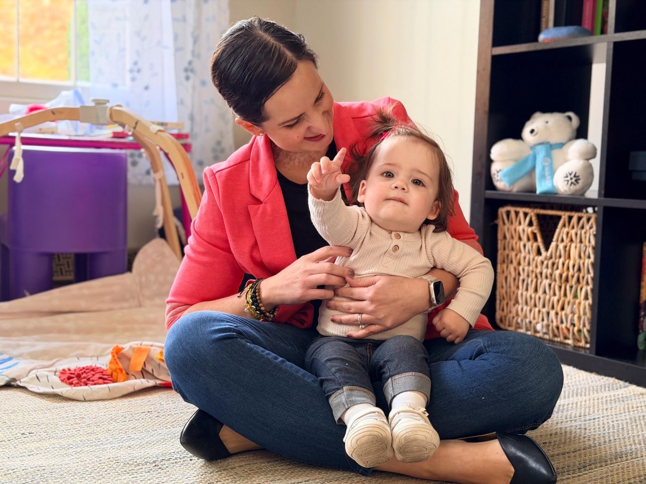 A mother sits in a playroom holding her child