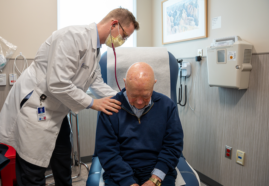 Dr. Patrck Seastedt holds a stethoscope to a male patient in clinic