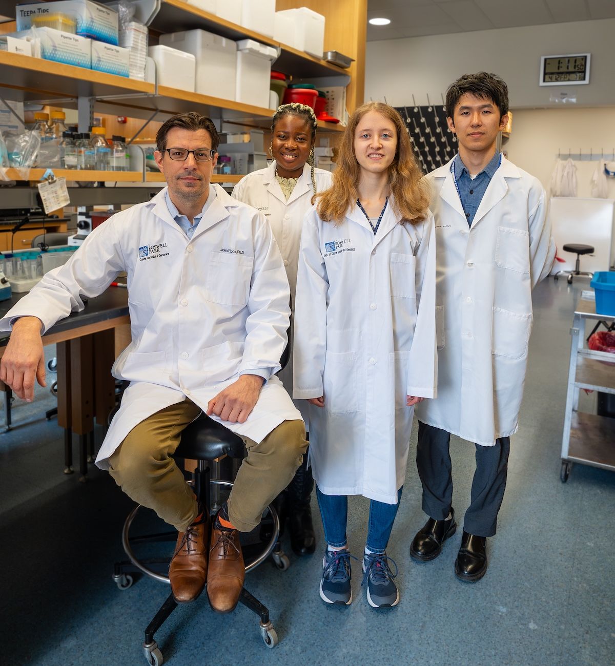 4 scientists stand beside a lab bench
