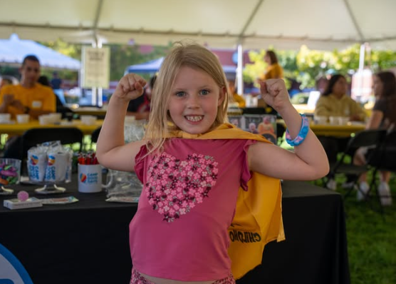 A young girl makes muscles during the One Gold event. 