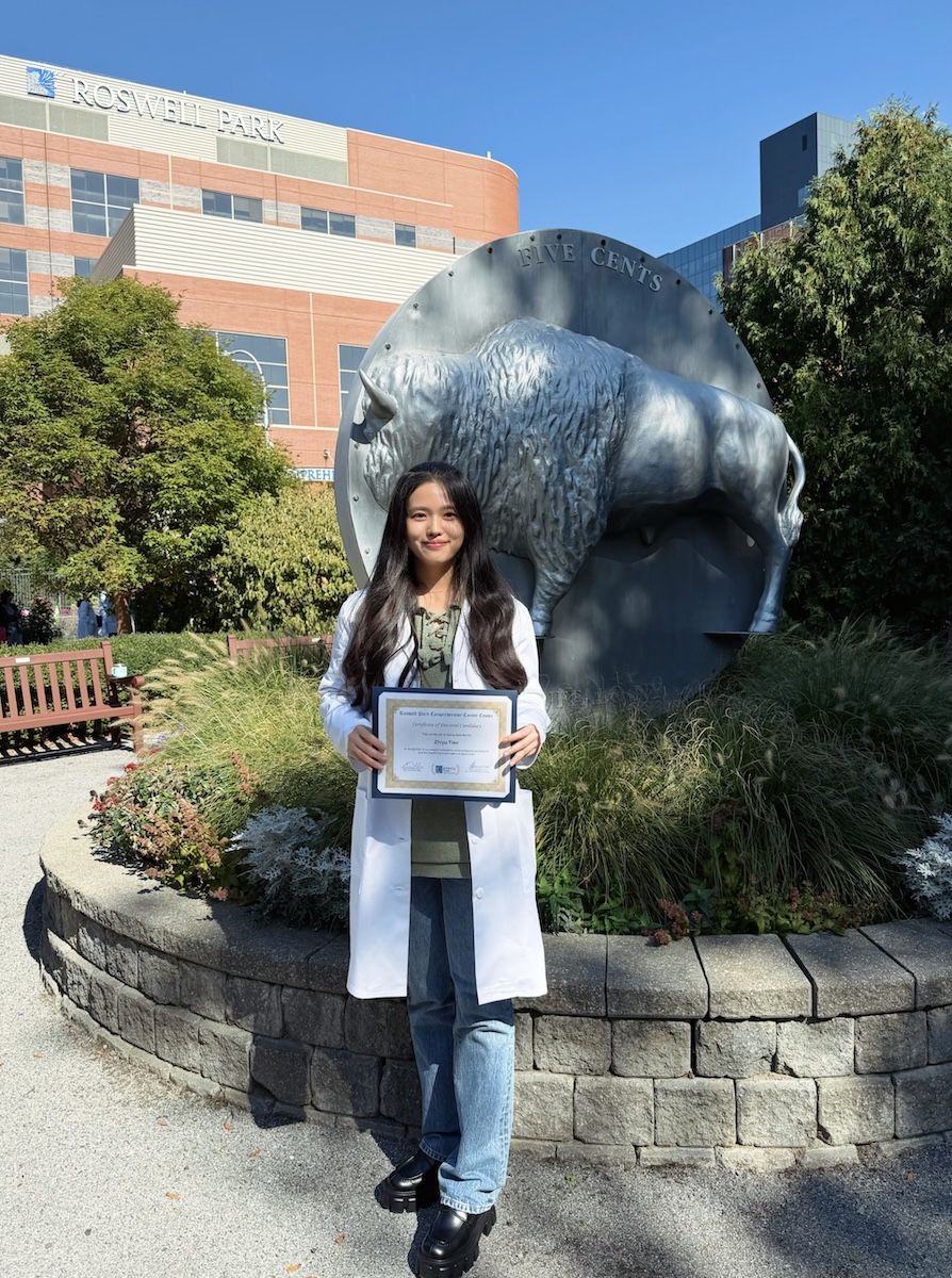 A scientist poses outdoors with her newly earned "white lab coat"