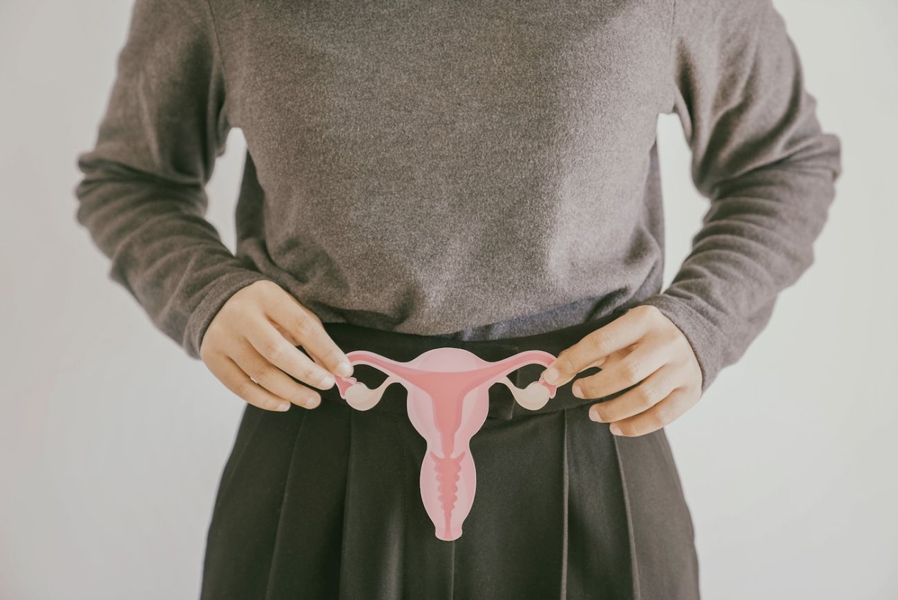 A woman holds a diagram of a uterus and ovaries