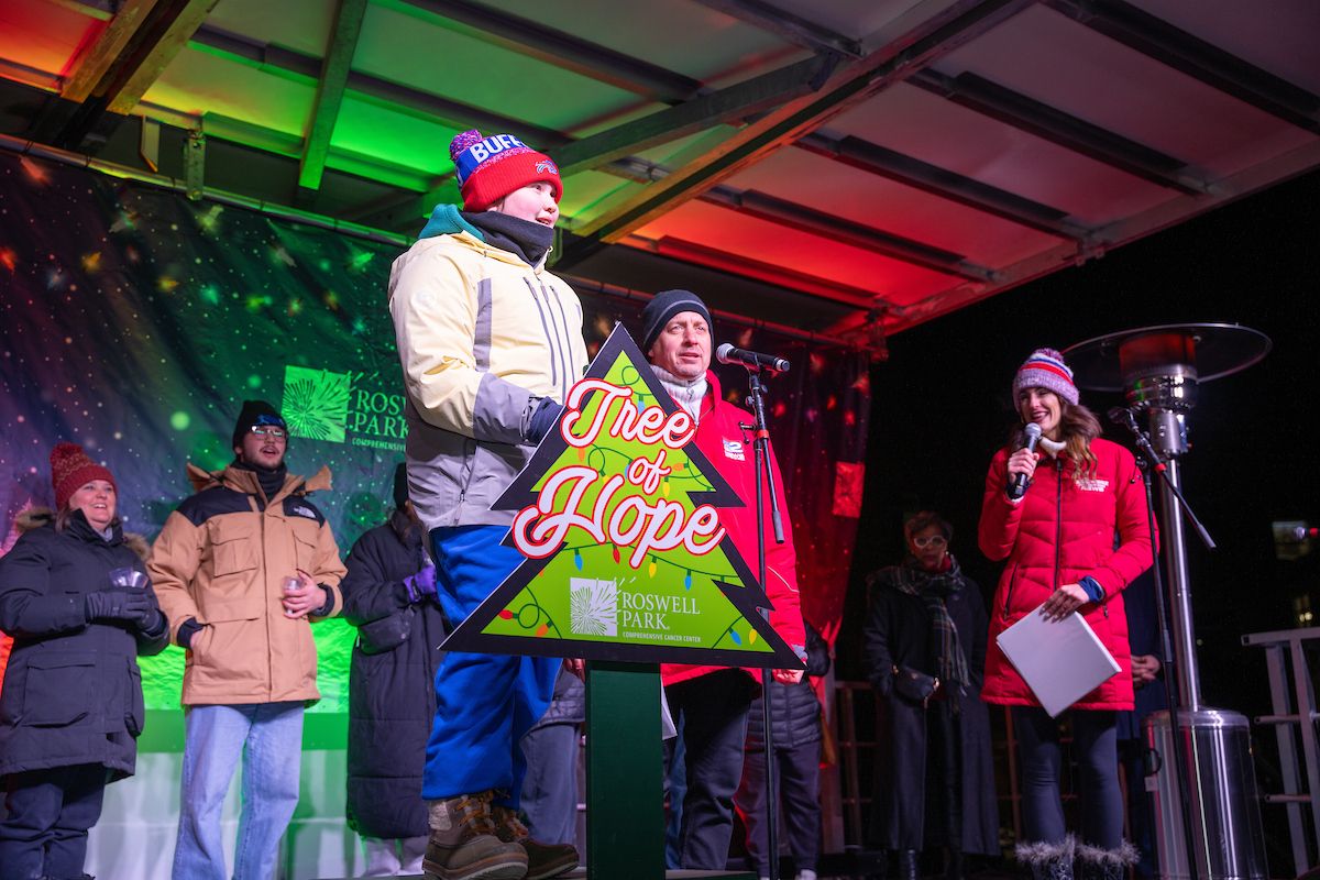 A child flips a switch to light a holiday tree