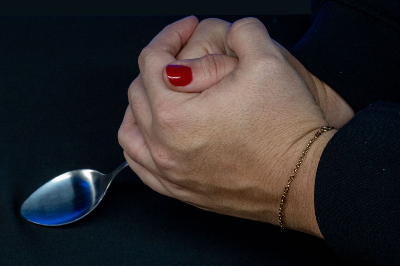 A set of hands pretends to bend a spoon as a magic trick