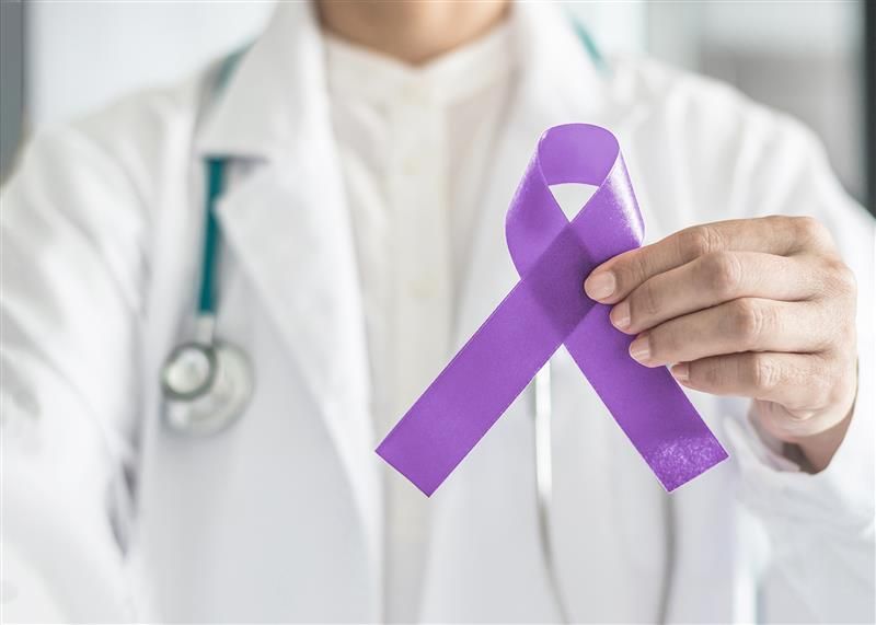 Doctor holding a purple testicular cancer ribbon