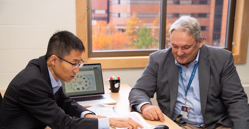 Two scientists discuss research in front of a computer