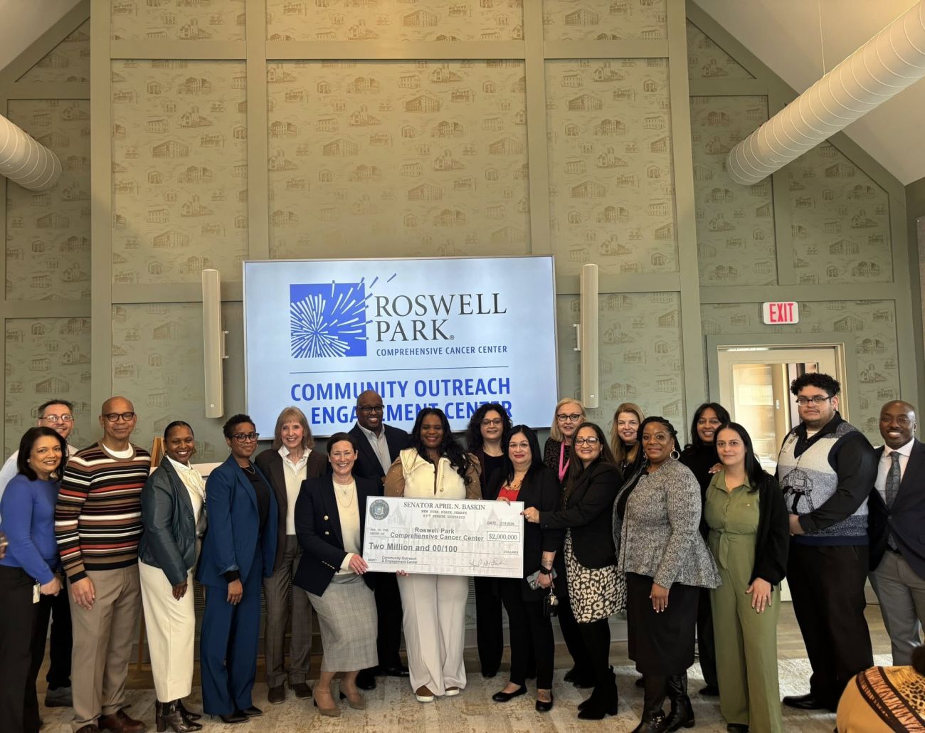 Group stands around government officials presenting a check