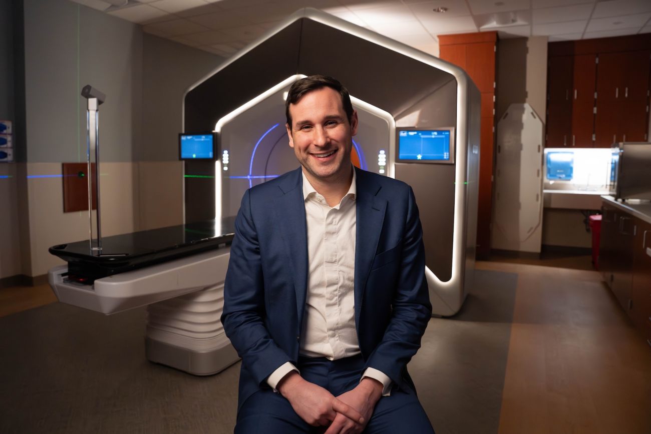 A doctor sits in front of a radiation machine to treat cancer.