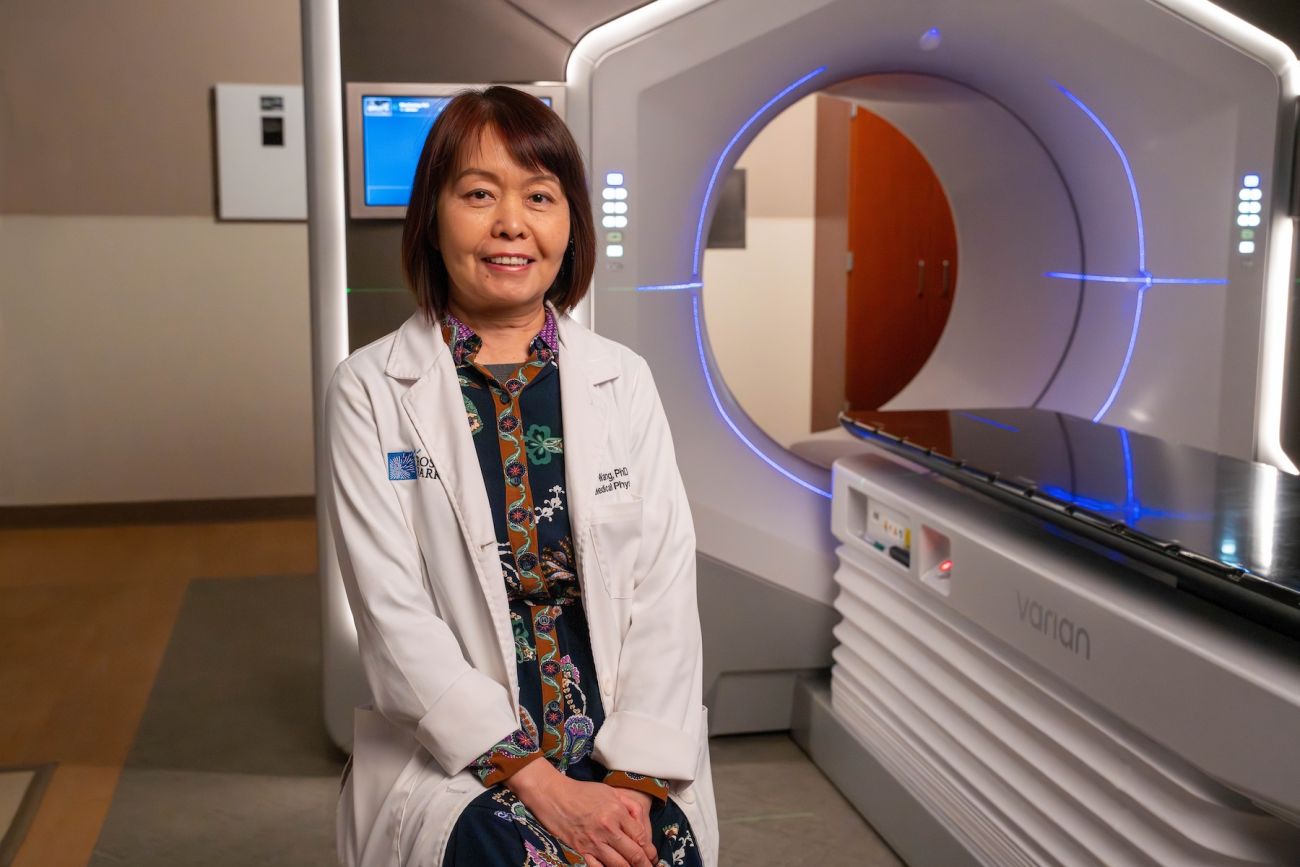 A doctor sits in front of a radiation machine to treat cancer.