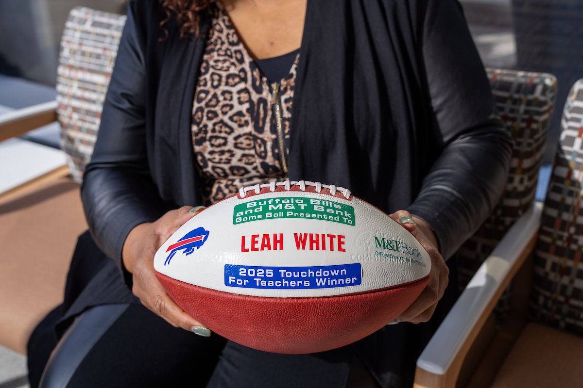A woman holding a football signifying her winning a teaching award.