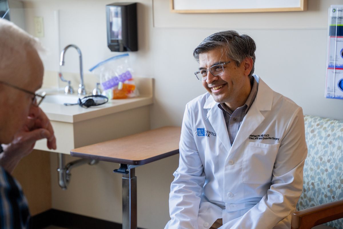 Dr. Marshaal Dhir smiles in clinic with a male patient