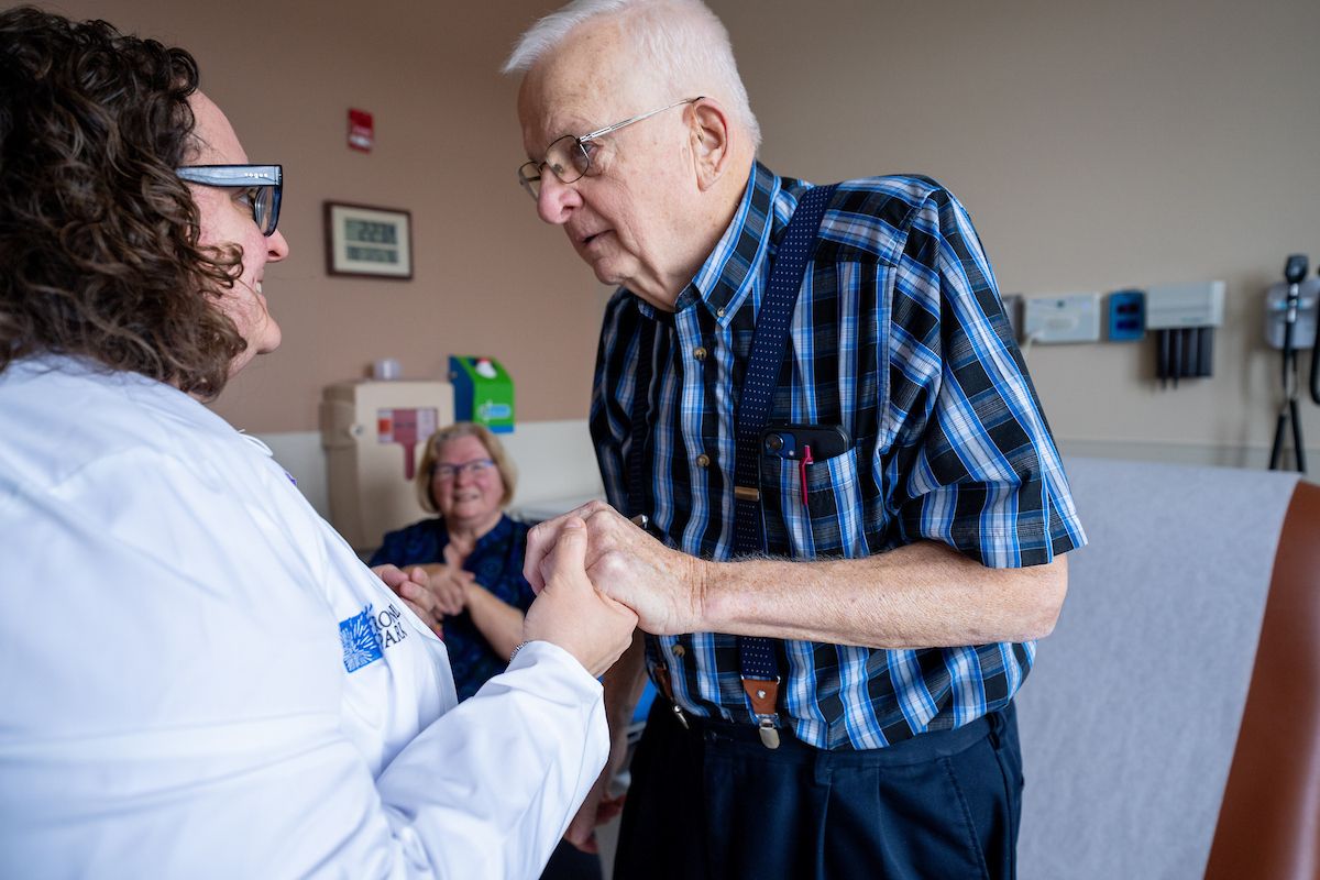 Dr. Desi Carozza holds hands with a male patient who is participating in the Older Adult Oncology Program