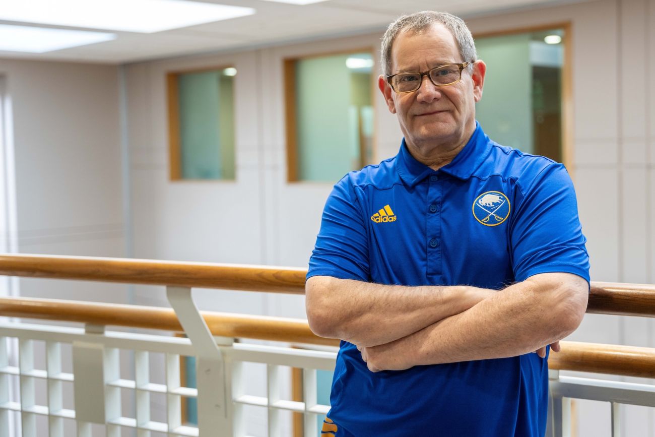A main stands on the railing overlooking a hospital atrium.