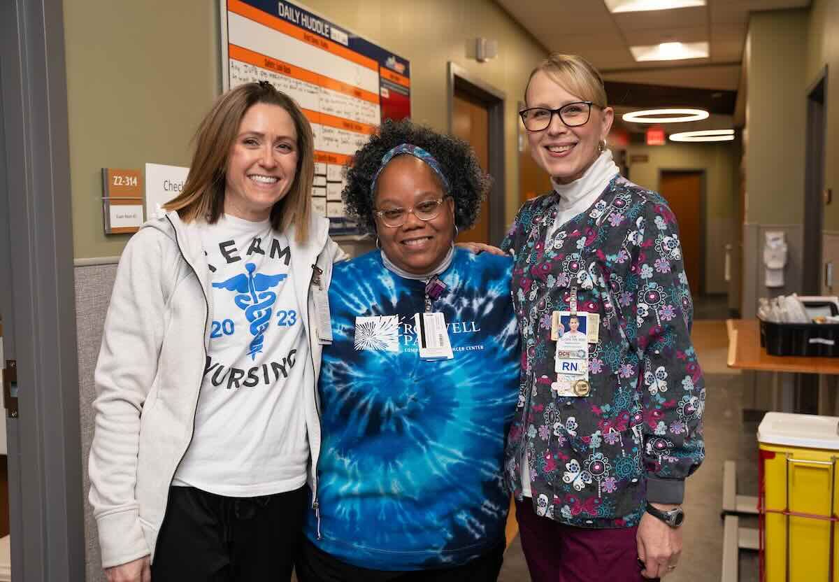 Three nurses stand in hospital hallway
