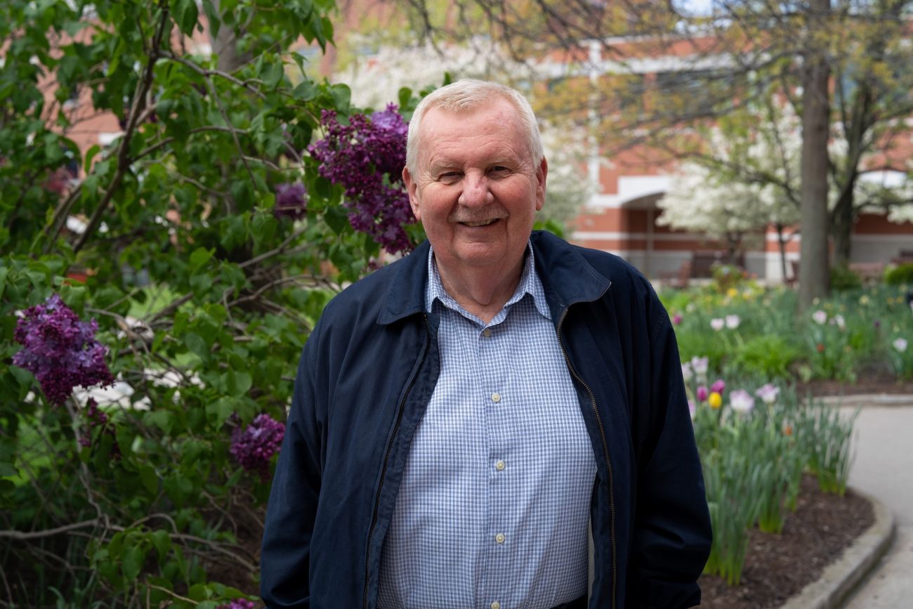 A man stands in a park near some flowers