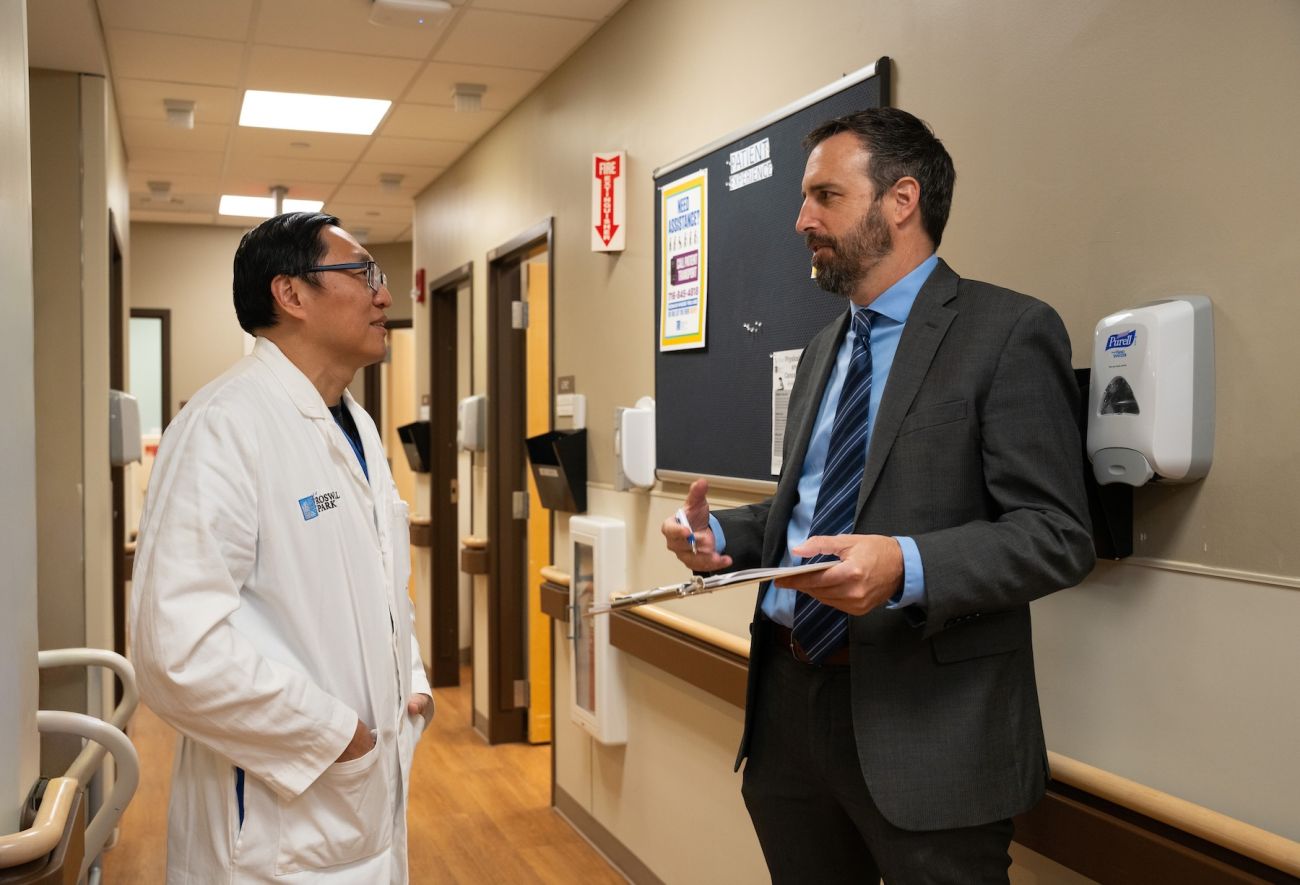 Two doctors discuss a patient in the hallway of a hospital.
