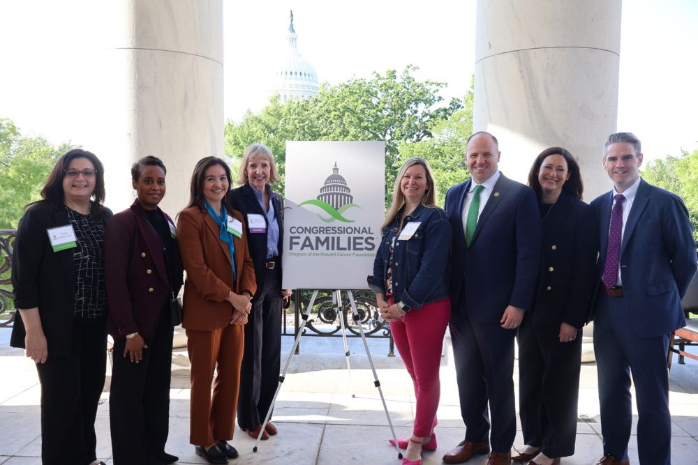 8 people stand with pillars and a poster on an easel