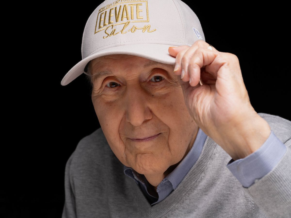 Joe Gadawski smiles to the camera wearing an Elevate Salon baseball hat