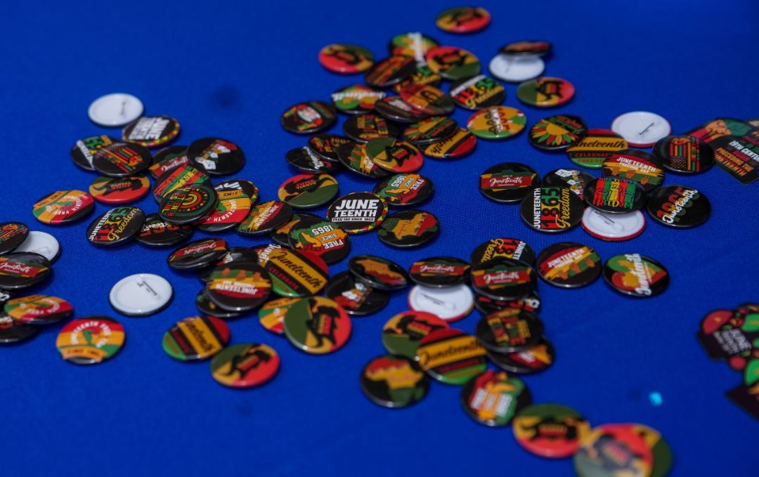 Buttons commemorate Juneteenth on a blue tablecloth. 