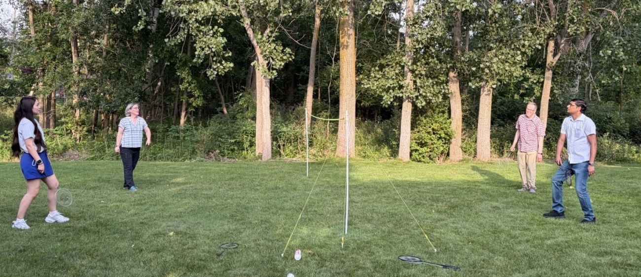 A group of friends plays badminton outdoors